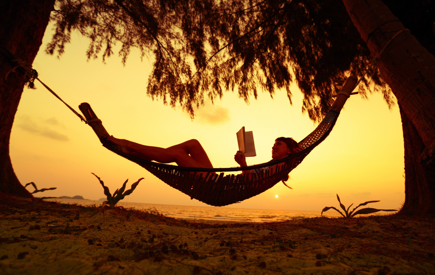 Frau liegt am Strand in einer Hängematte und liest im Sonnenuntergang ein Buch; Kurtz Detektei Düsseldorf, Detektiv Düsseldorf, Detektivbüro in Düsseldorf