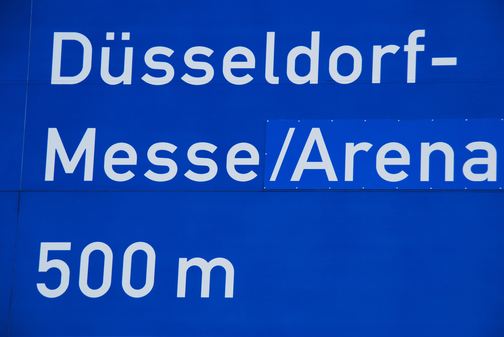 Blaues Verkehrsschild "Düsseldorf-Messe/Arena 500 m"; Kurtz Detektei Düsseldorf, Detektivagentur Düsseldorf, Detektiv aus Düsseldorf