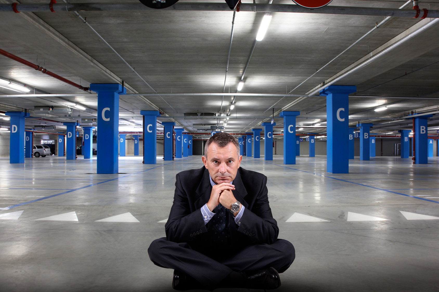 Ein Mann sitzt deprimiert auf einem leeren Parkplatz in einer Tiefgarage; Kurtz Detektei Düsseldorf