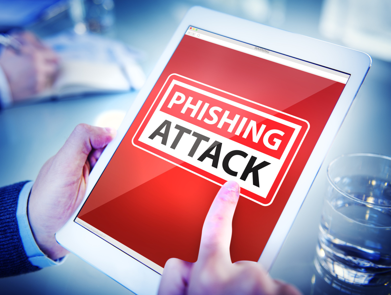 Banner "Phishing Attack" auf dem Display eines Tablets in den Händen eines Mannes im Anzug; IT-Sicherheit Kurtz Detektei Düsseldorf, IT-Experte Düsseldorf, IT-Spezialist Düsseldorf, IT-Service Düsseldorf